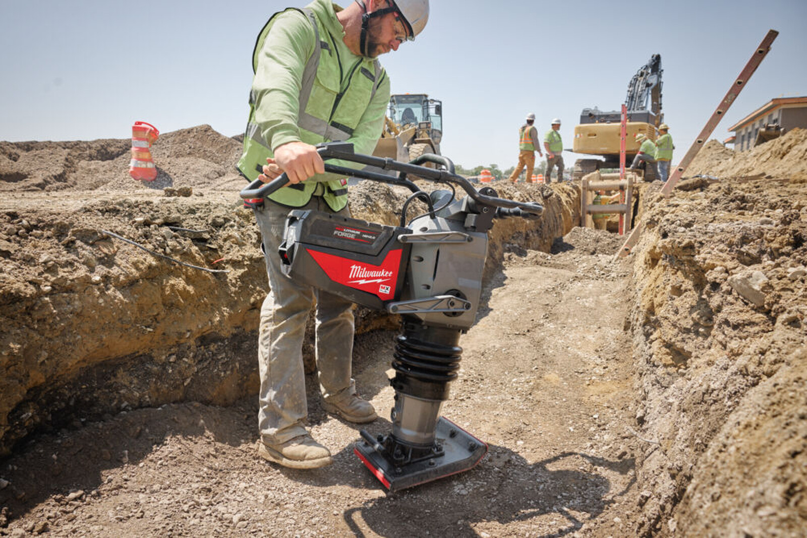 Pildil on ehitustöölise poolt kasutatav Milwaukee akutoitel vibroplaat MXF RAM60-0, mis tihendab pinnast kaevikus.