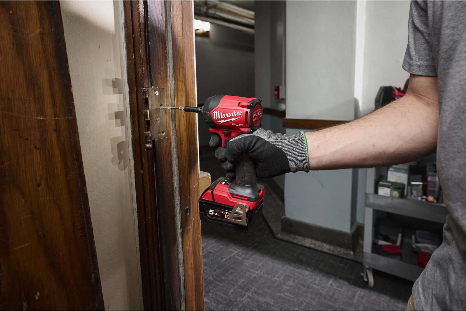 Pildil on näha, kuidas inimene kasutab Milwaukee hüdraulilist akulöökkruvikeerajat M18 FIDRQ-0X uksehinge kruvide...