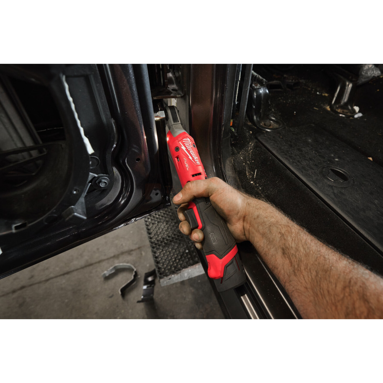 Pildil on mees, kes kasutab Milwaukee akunarret M12 FIR14G2-252B auto ukse juures.