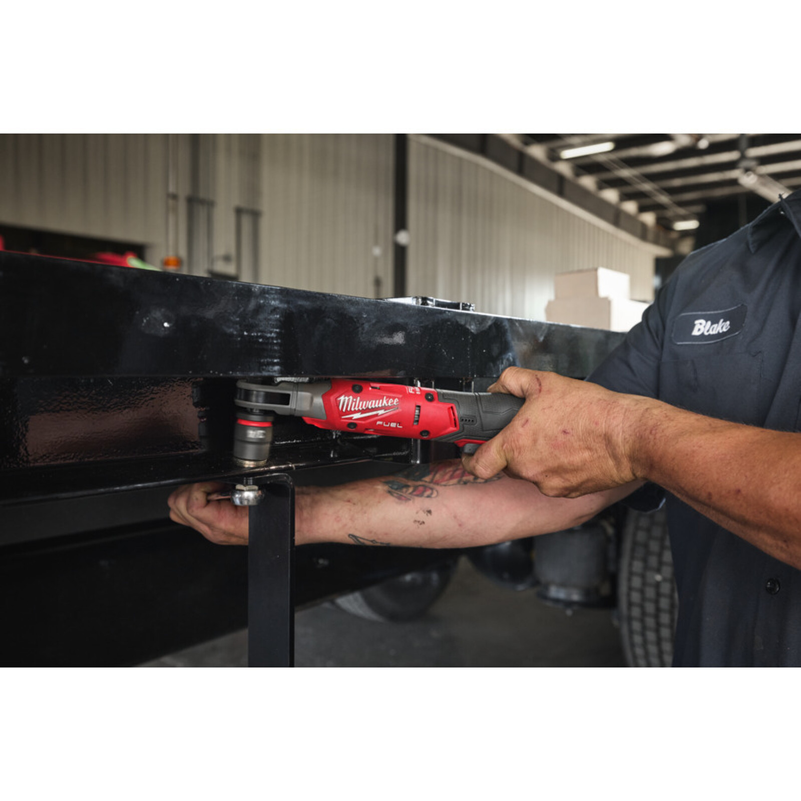Pildil on mees, kes kasutab Milwaukee akunarret M12 FIR12G2-252B, et kinnitada polti suurele metallkonstruktsioonile.