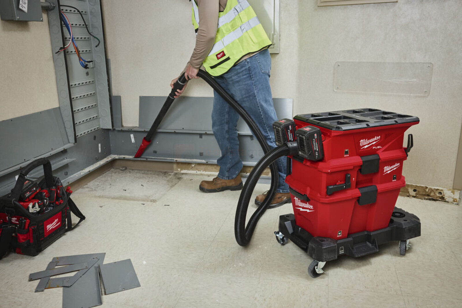 Pildil on ehitustöölise poolt kasutatav Milwaukee akuga vee- ja tolmuimeja, mis on paigutatud ratastega alusele ja...