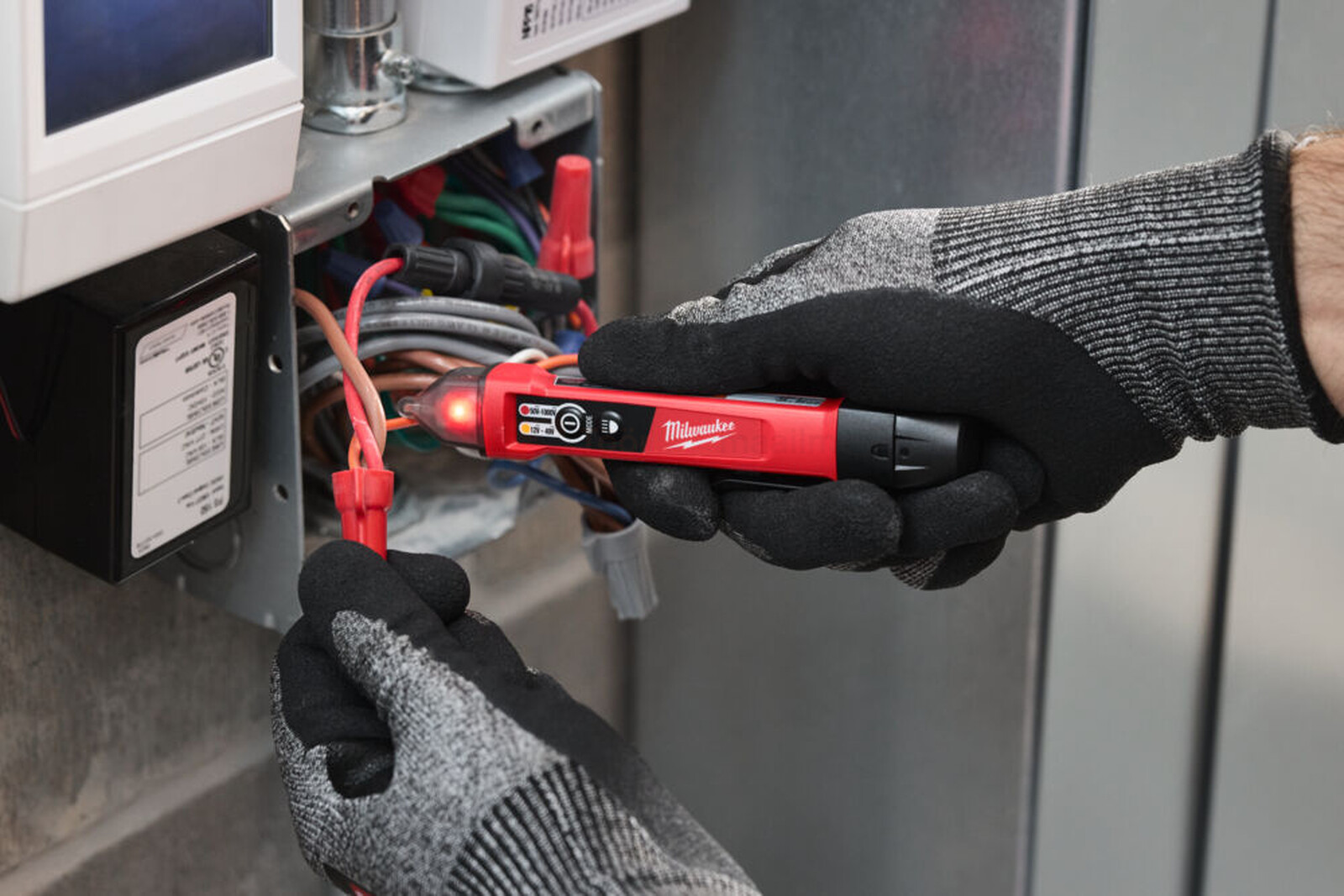 Pildil kasutab käes kinnastatud elektrik Milwaukee pingedetektor-taskulampi NCVDDF, et kontrollida pinge olemasolu...