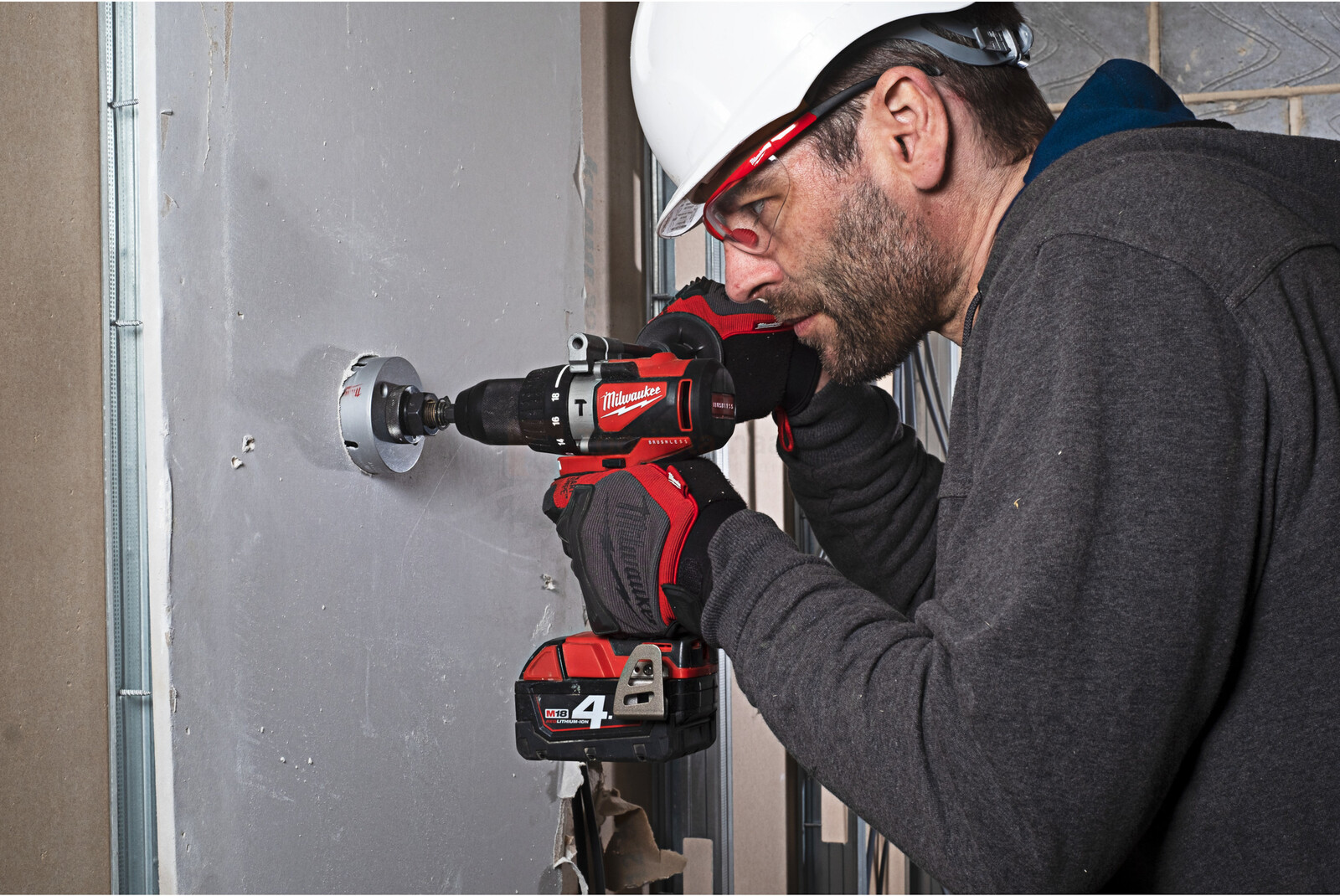 Pildil on mees, kes kasutab Milwaukee akulööktrelli M18 BLPD2-501B, et puurida auku seina.