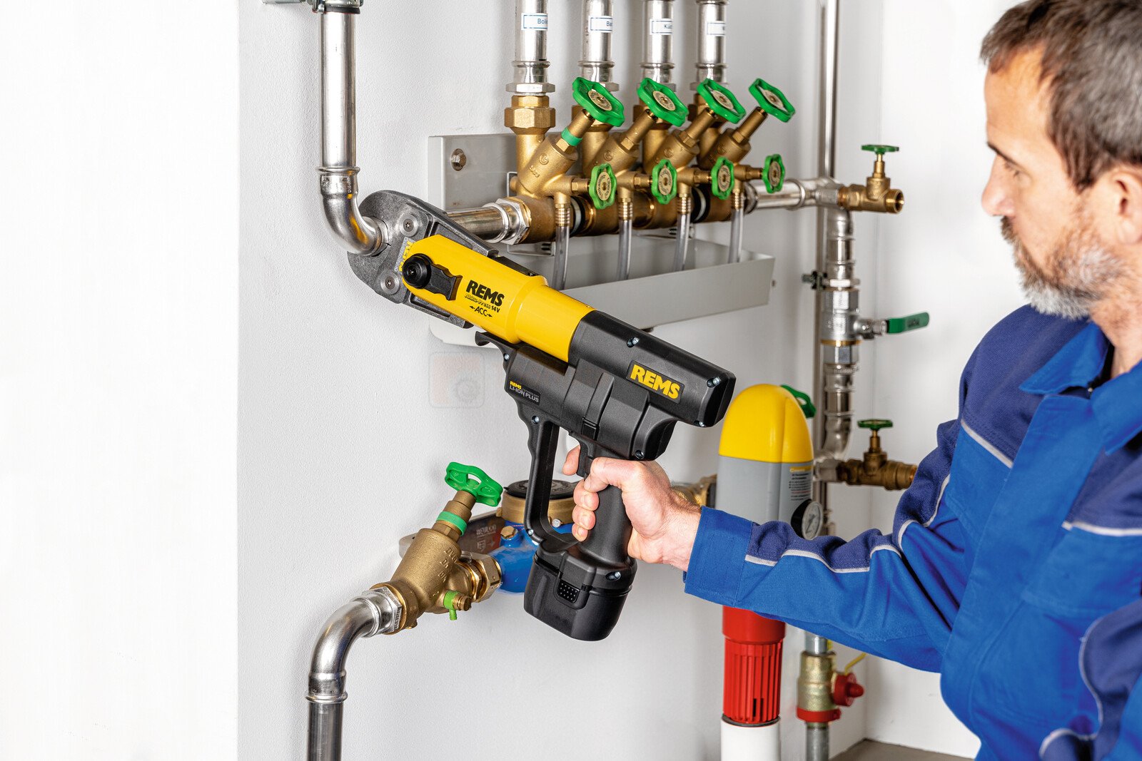 Pildil on torumees, kes kasutab REMS torupressi Akku-Press 14V ACC Basic-Pack, et pressida toru liiteid.