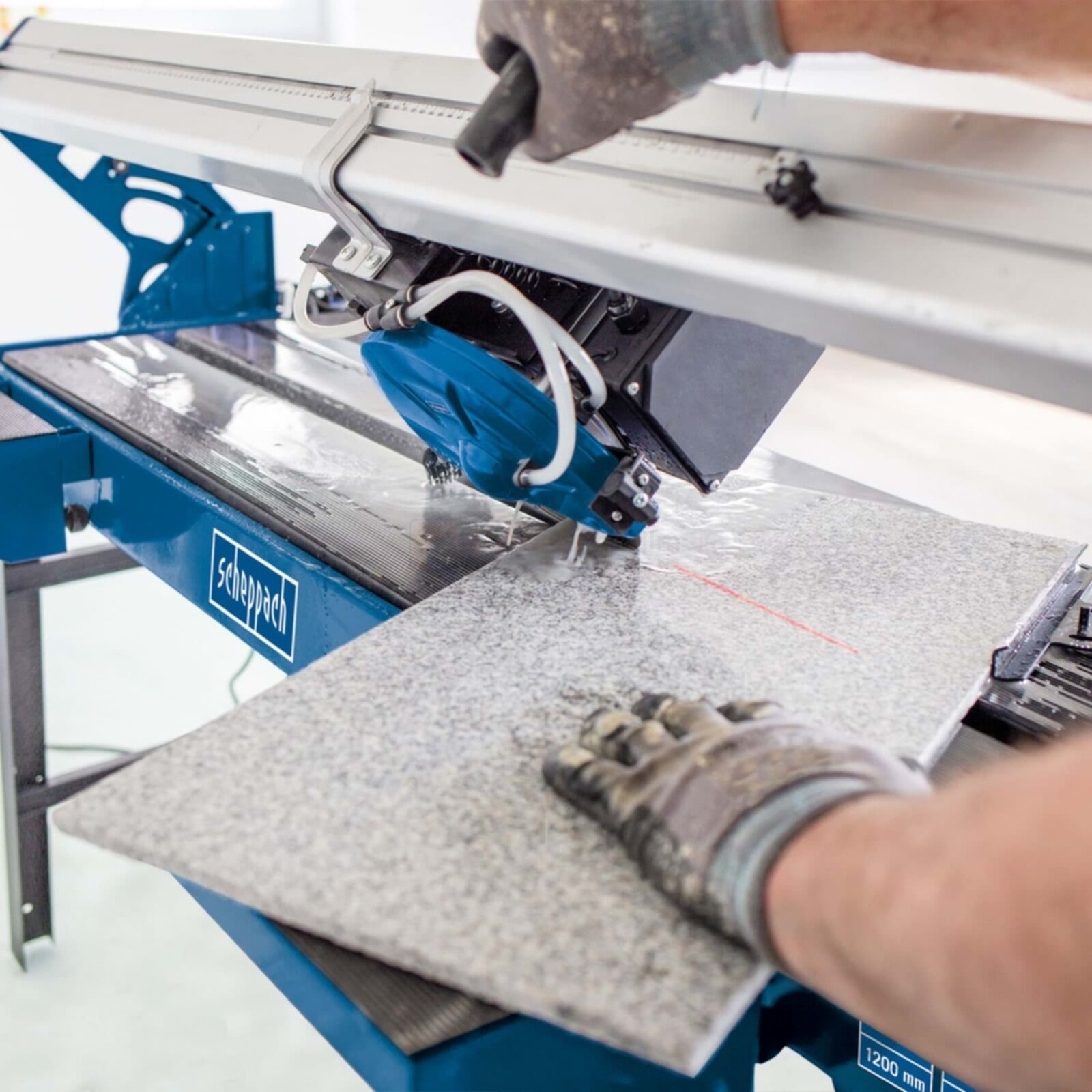 Pildil on näha, kuidas töötaja lõikab Scheppach FS 3600 veega plaadilõikuriga keraamilist plaati.