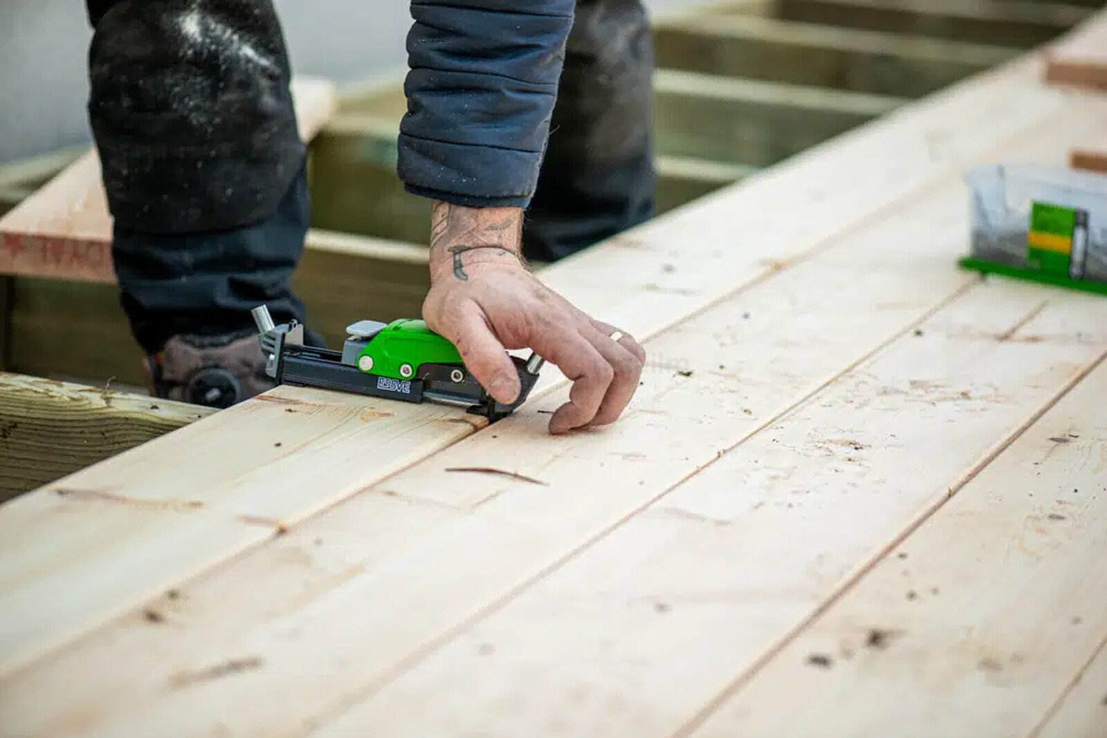 Pildil on ehitaja, kes kasutab Essve terrassikruvi paigaldusrakist HDS PRO 105/155 terrassilaudade paigaldamisel.