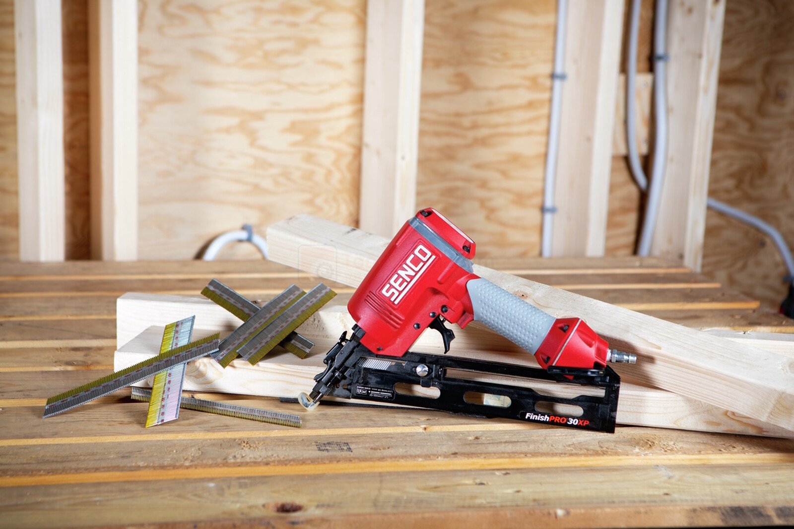 Pildil on SENCO FinishPro30XP liistunaelapüstol koos naeltega, mis on asetatud puidule, viidates selle kasutamisele...