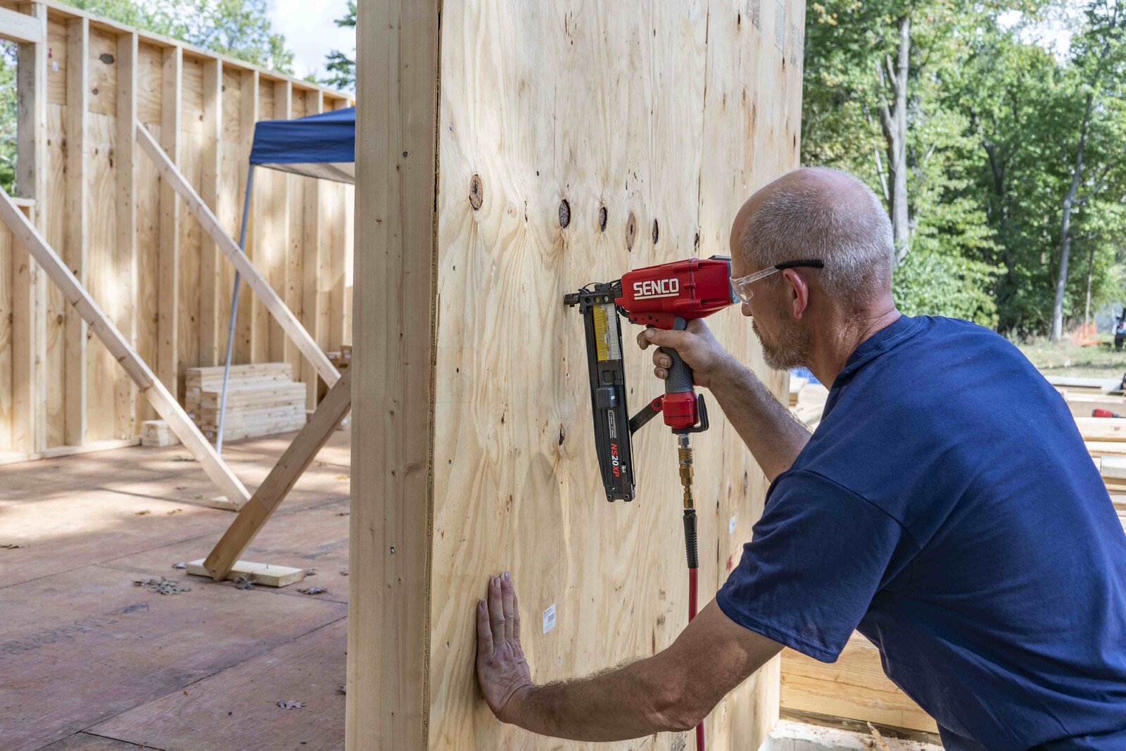 Pildil on mees, kes kasutab SENCO klambripüstolit PS20XP, et kinnitada puitkonstruktsioonile puitu.