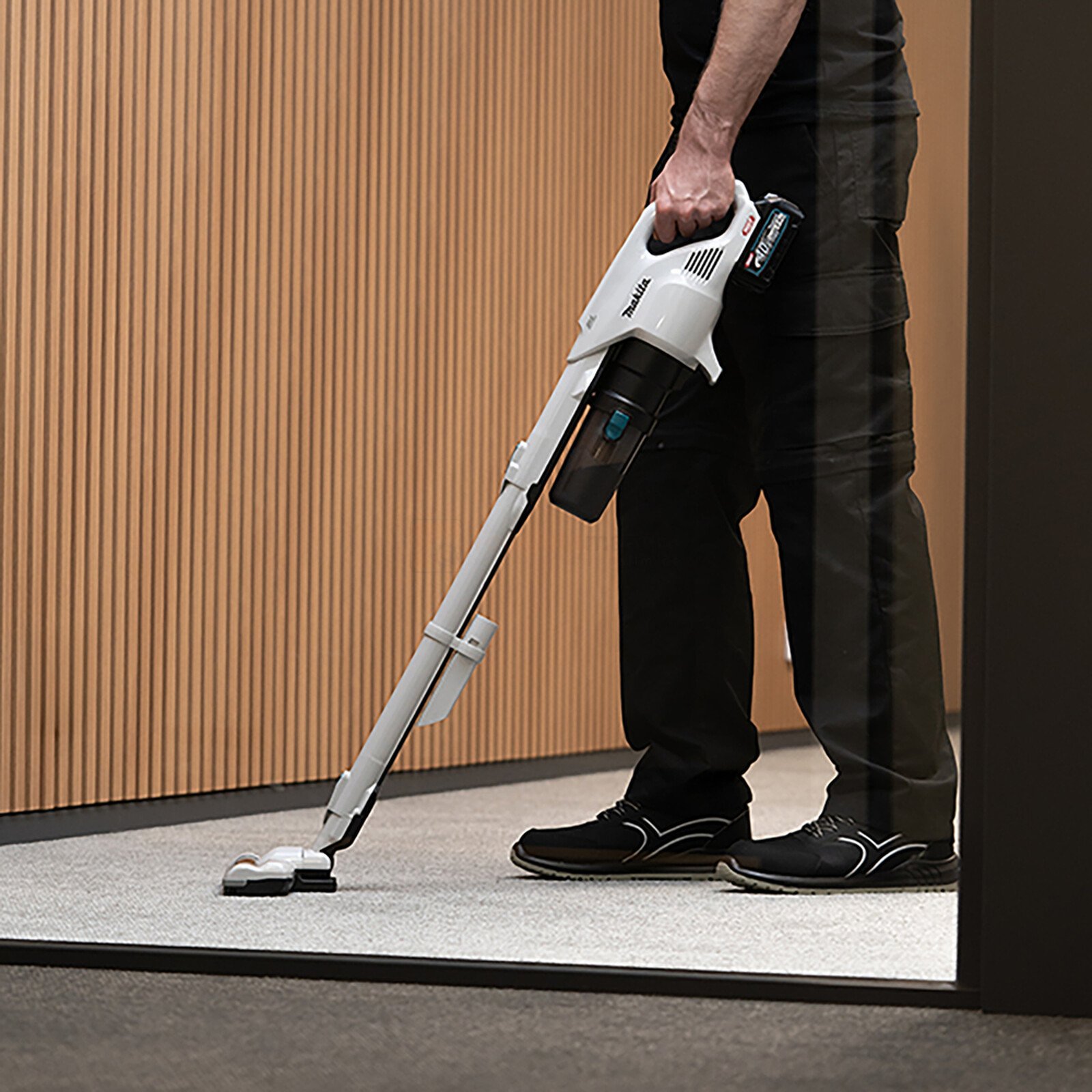 Pildil on mees, kes kasutab Makita aku varstolmuimejat CL004GZ, mis on XGT seeria ja ilma aku ja laadijata, puhastades vaipa.