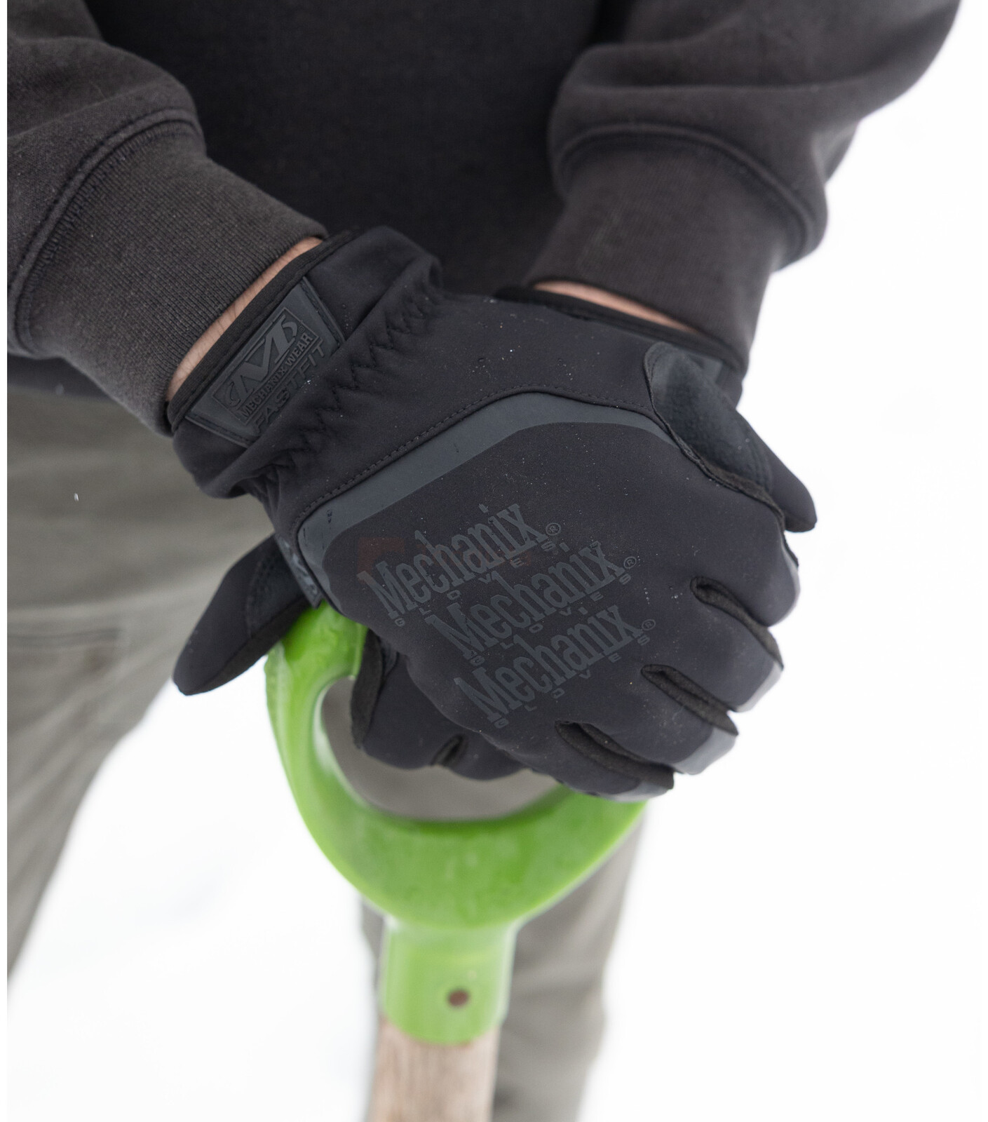 Pildil on näha mustad MECHANIX WEAR ColdWork FastFit Covert talvised kindad, mida kannab inimene, kes hoiab rohelise...