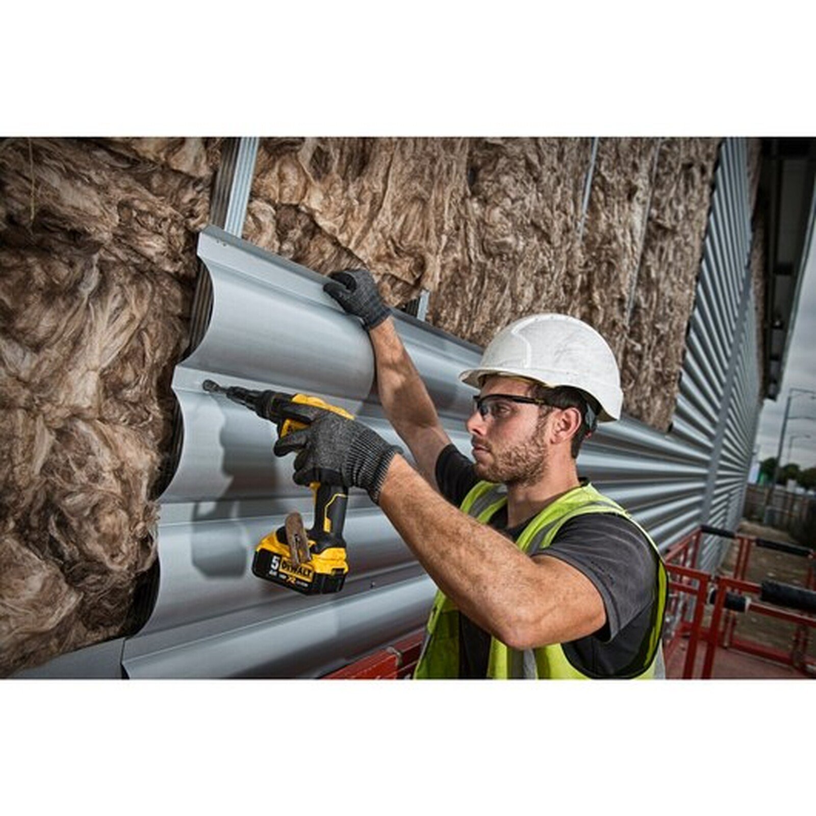 Pildil on ehitaja, kes kasutab DeWalt DCF622N akukruvikeerajat isepuurivate kruvide jaoks, et kinnitada materjali hoone...