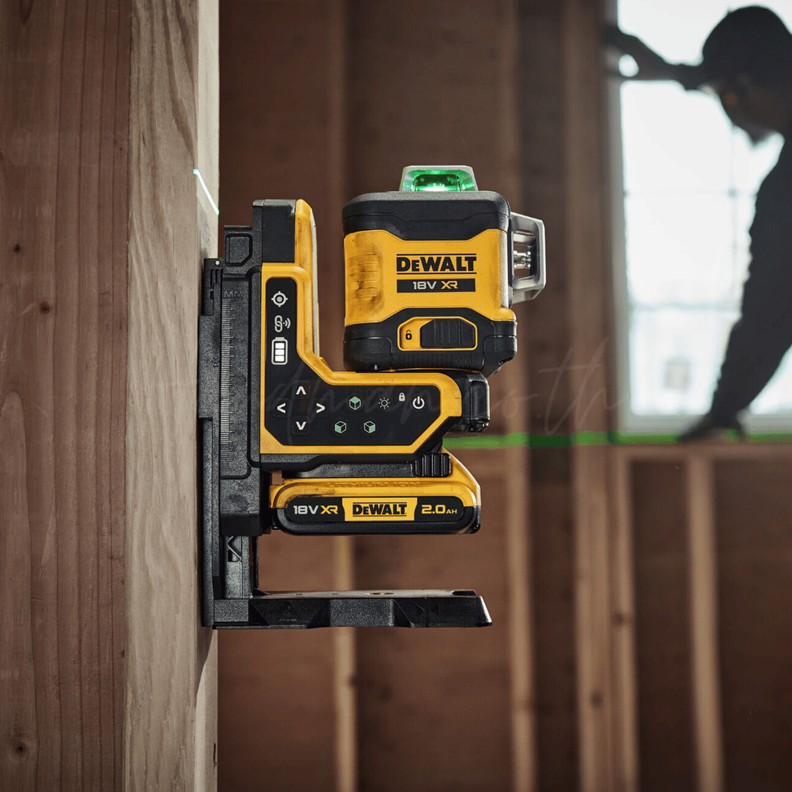 Pildil on DeWalt ristlaser, mis on kinnitatud puidule ja projekteerib rohelise laserjoone, samal ajal kui taustal on näha...