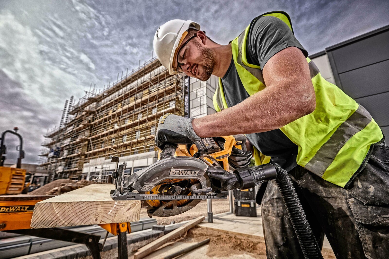 Pildil on ehitustöölise poolt kasutatav DeWalt Flexvolt DCS577N akuketassaag, mis lõikab puitu ehitusplatsil.