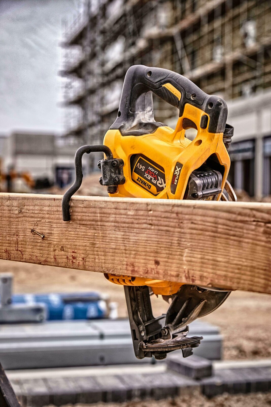 Pildil on näha kollane DeWalt Flexvolt DCS577N akuketassaag, mis on kinnitatud puidust detaili külge ehitusplatsil.