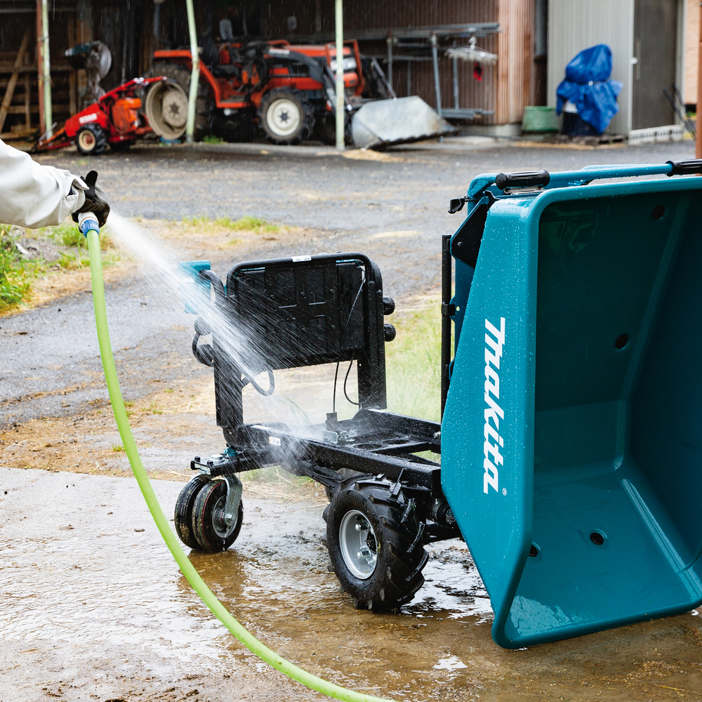 Pildil on Makita akutoitega aiakäru DCU603Z, ilma aku ja laadijata, mida pestakse voolikust veega.