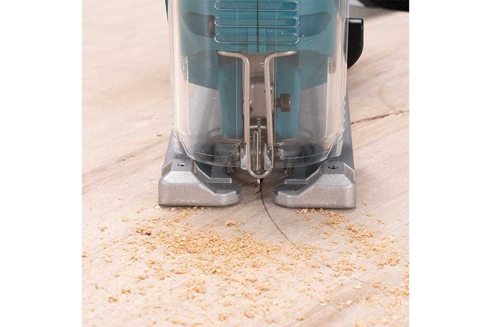 Pildil on Makita akutikksaag DJV186Z, mis on puidu peal ja saeb seda, tekitades saepuru.