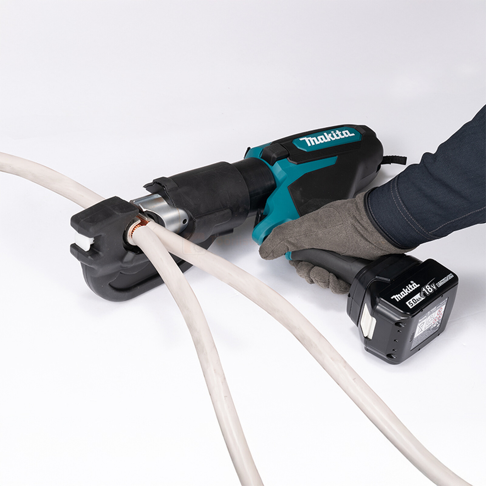 Pildil on näha Makita akukaablipress DTC301ZK, mida kasutatakse kaablite ühendamiseks, koos sellega töötava käega.