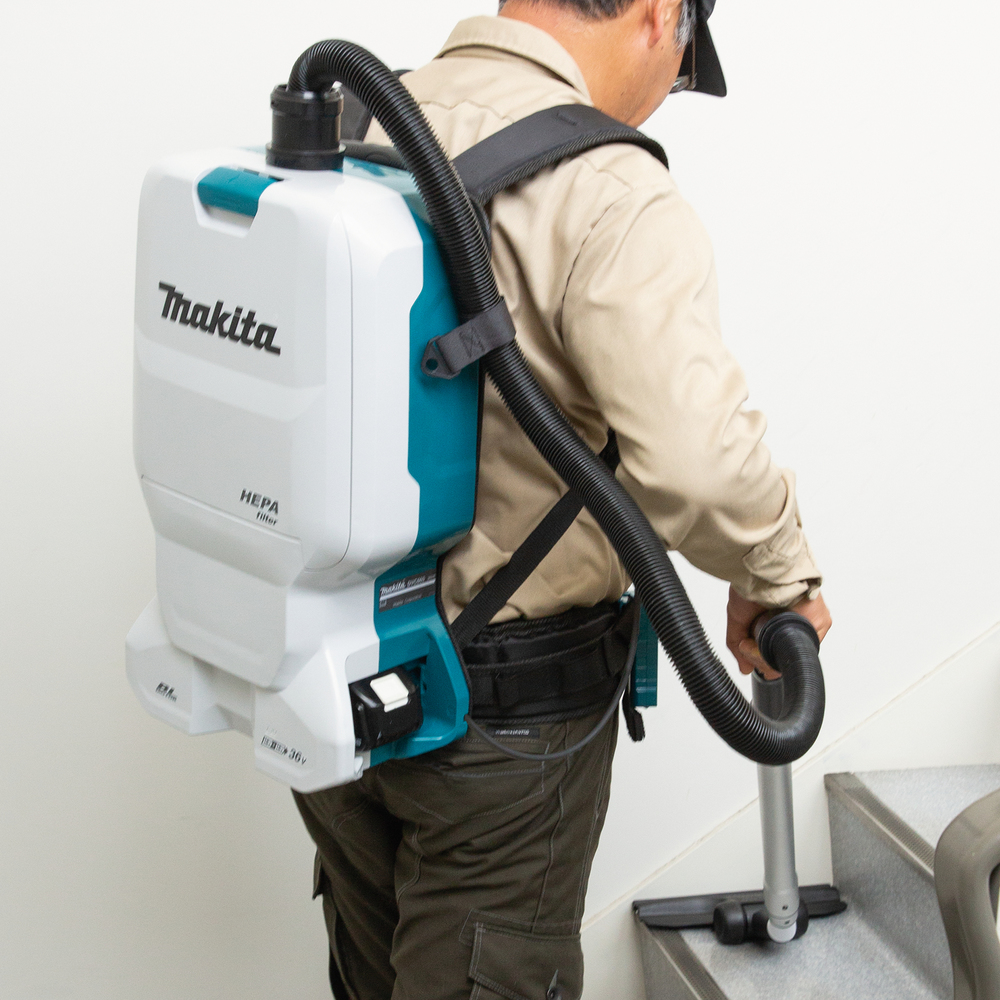 Pildil on Makita DVC660Z akutolmuimeja, millega inimene puhastab trepiastmeid.