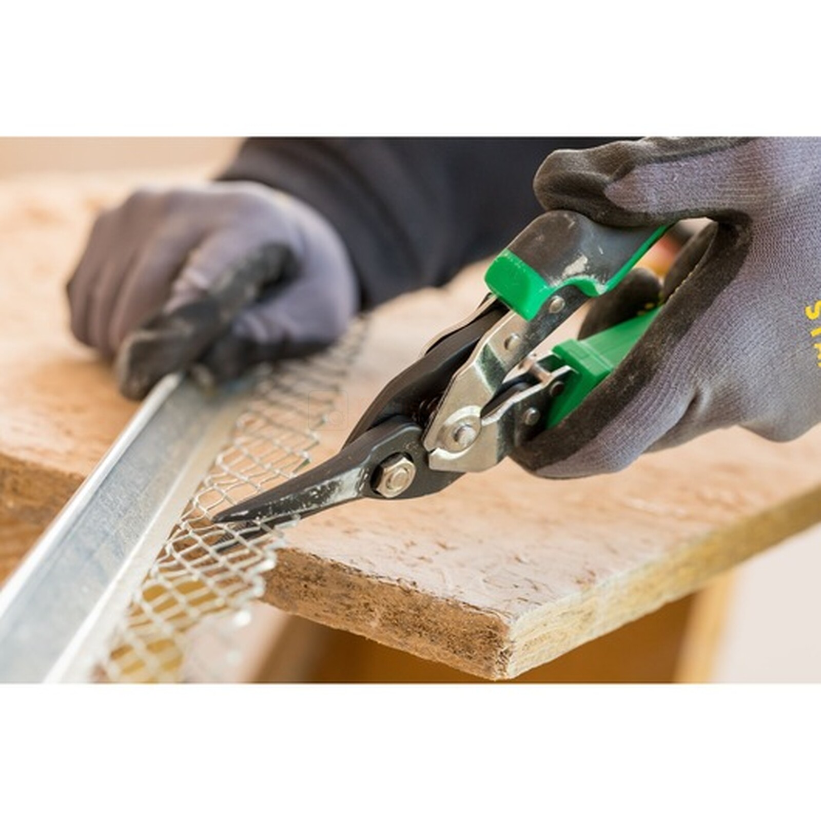 Pildil on näha, kuidas töömees kasutab Stanley FATMAX 250 mm paremaid plekikääre, et lõigata metallvõrku.