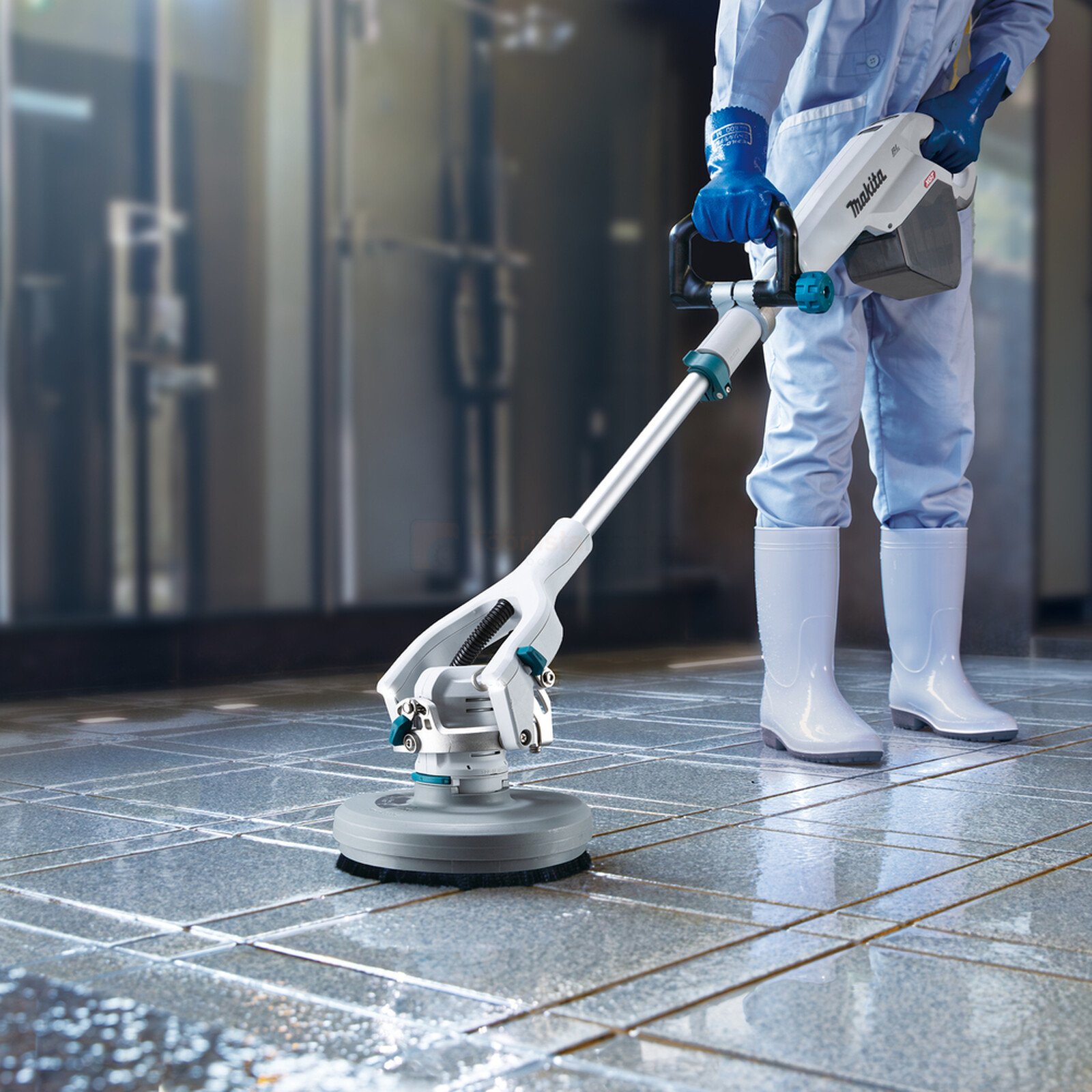 Pildil on Makita akutoitel põrandahooldusmasin PS001GZ, mida kasutab töötaja põrandate puhastamiseks.