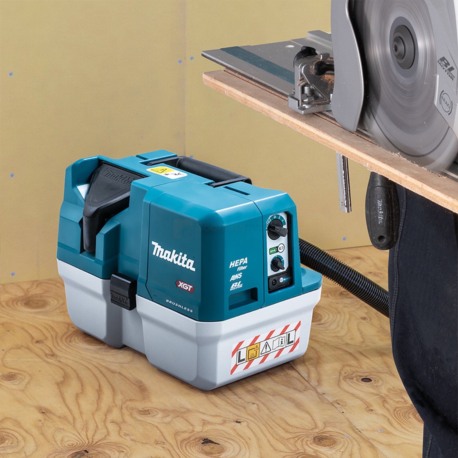 Pildil on Makita akutoitel vee- ja tolmuimeja VC013GLZ, mis on ühendatud saega, et imeda tolmu saagimise ajal.