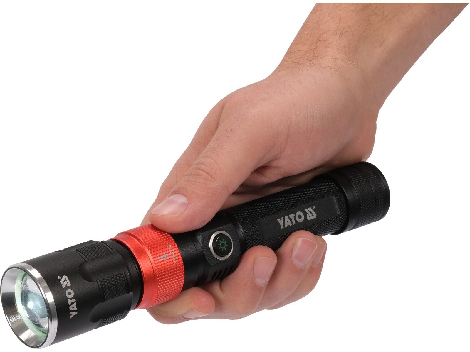 Pildil on käes hoitud YATO LED töövalgusti, mis on musta värvi ja millel on punane rõngas.