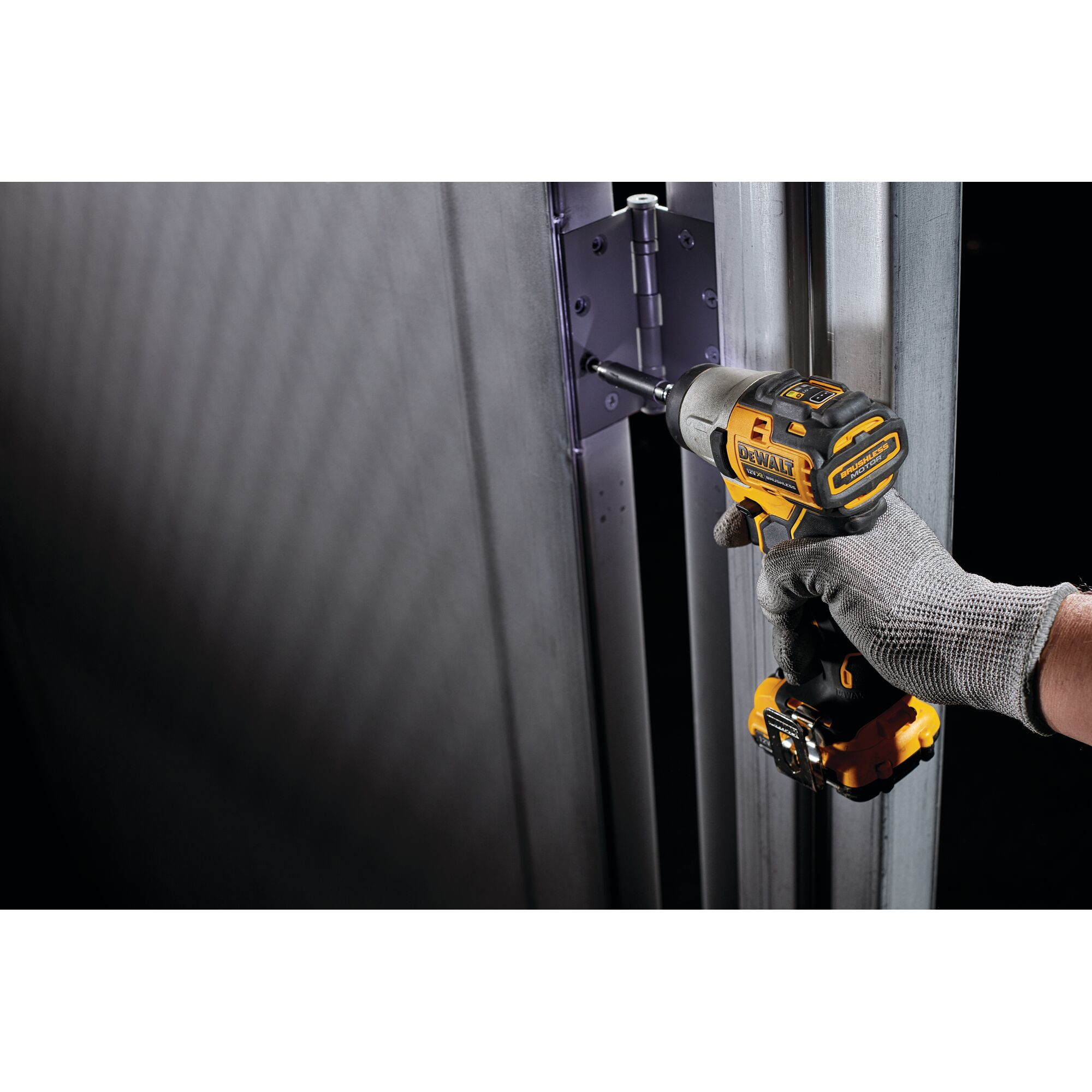 Pildil on DeWalt akulöökkruvikeeraja DCF801N, millega kruvitakse polti uksehinge külge, samal ajal kui kasutaja kannab...