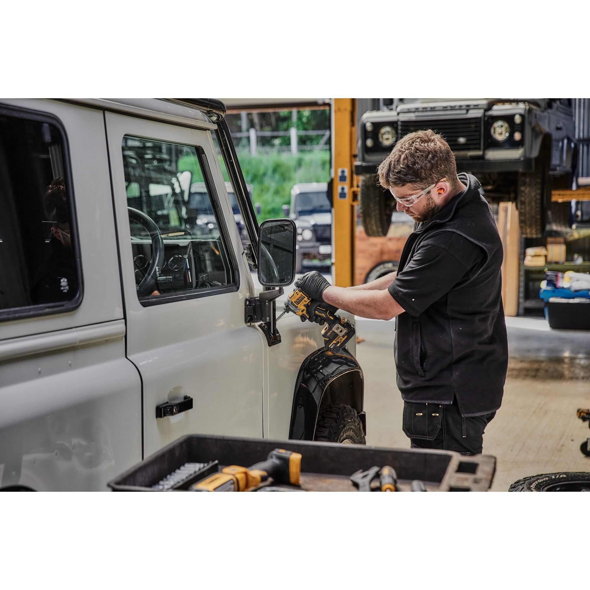 Pildil on mees, kes kasutab DeWalt akulöökkruvikeerajat DCF850N ilma aku ja laadijata, et kinnitada auto küljepeeglit.