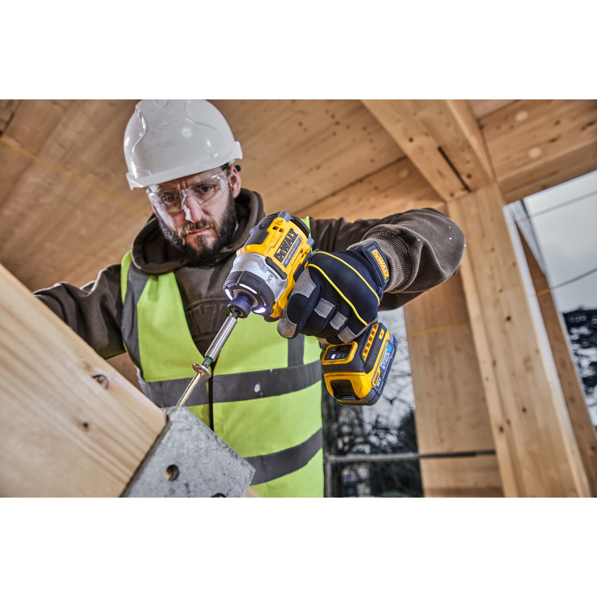 Pildil on ehitustööline, kes kasutab DeWalt akulöökkruvikeerajat DCF860N, kruvides puitelementi.