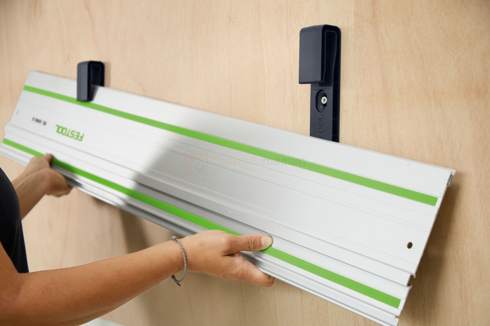 Pildil on näha, kuidas inimene paigaldab Festool juhtsiini hoidikusse HA-FS/2 juhtsiini.