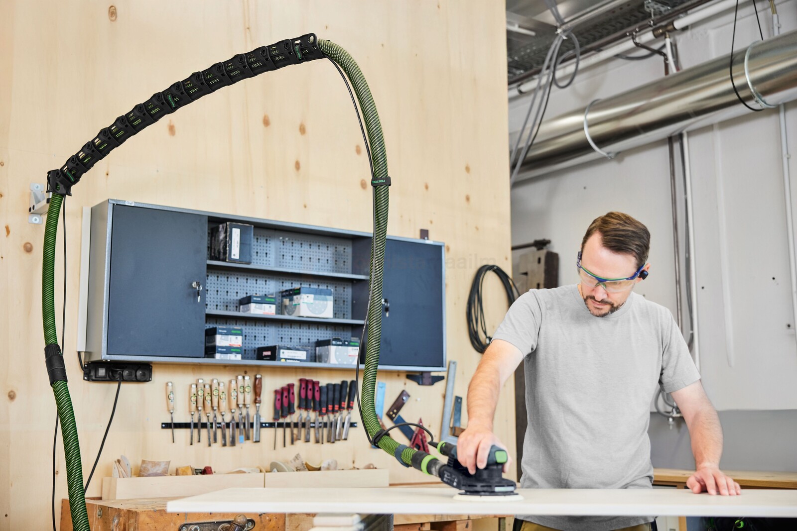 Pildil on mees, kes kasutab Festool tolmuimemise poomi CT-ASA FLX W, et lihvida puidutööd, samal ajal kui tolmuimemise...