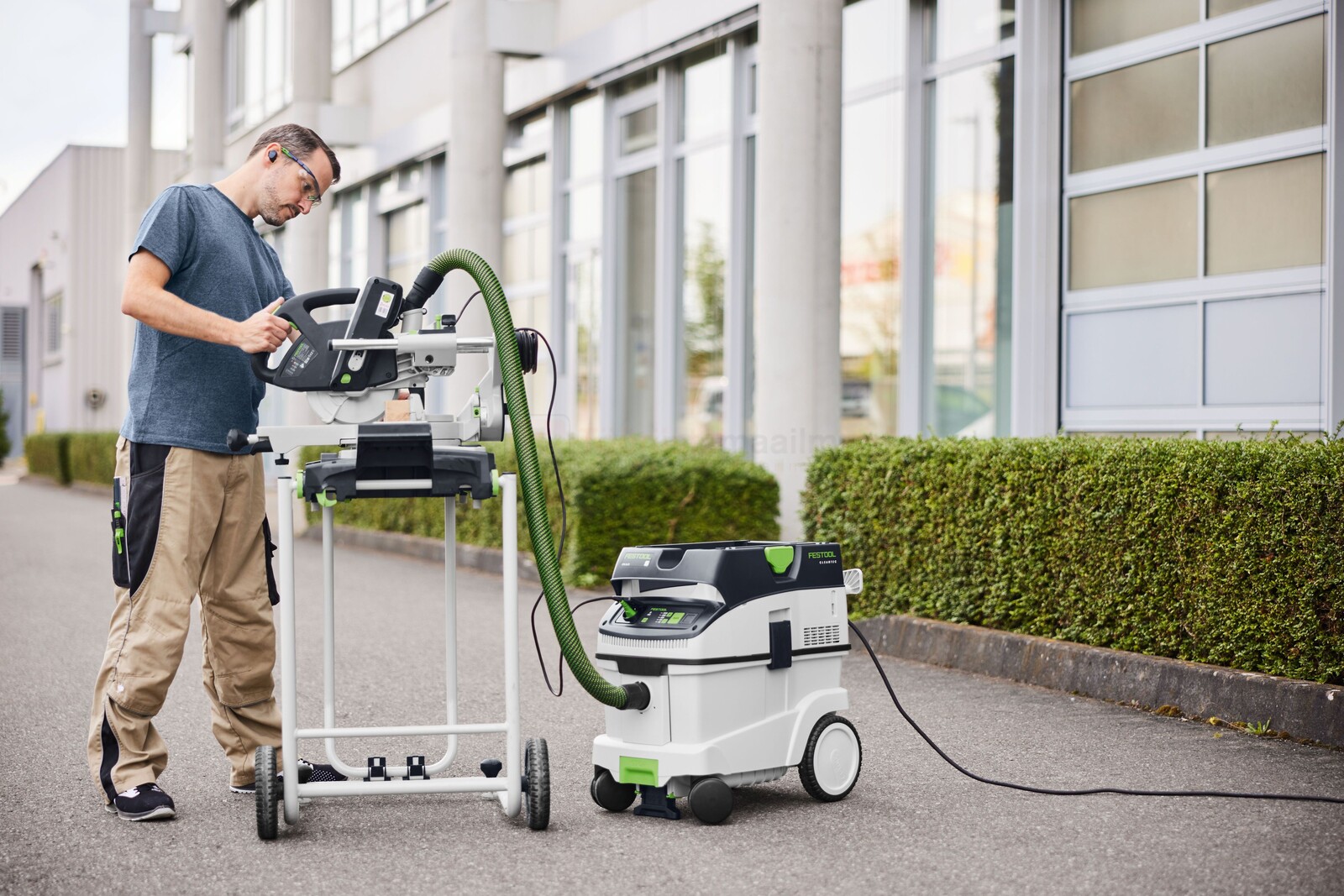 Pildil on mees, kes kasutab Festool imivoolikut D36x1,4m-AS/CTR koos saega, et lõigata puitu õues, samal ajal kui...