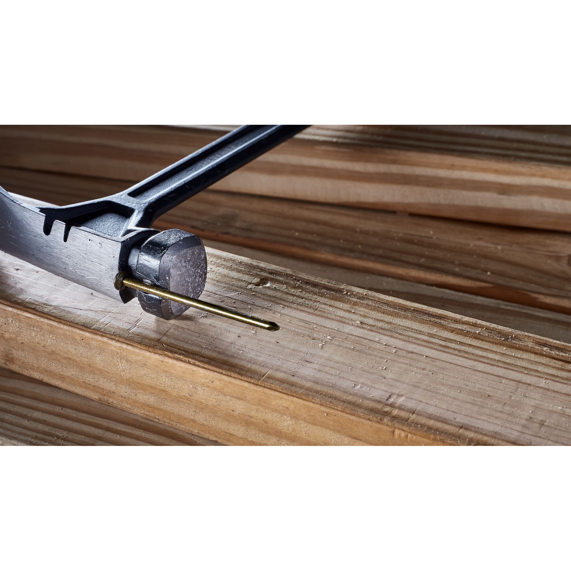 Pildil on DeWalt sõrgvasar 624 g, sileda peaga, mis on asetatud puitlauale ja millega on peaaegu löödud nael puitu.