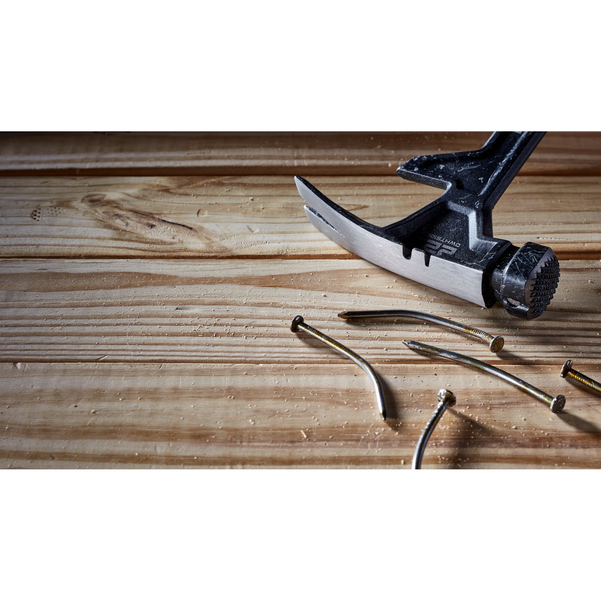 Pildil on DeWalt lammutusvasar 624 g, millega on saetud puitu, mõned kõverad naelad ja puidust laud.
