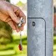 Pildil on käsi, mis hoiab KNIPEX standardvõtit hoonete tehniliste seadmete jaoks, millega avatakse metallist posti luuk.