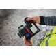 Pildil on näha, kuidas inimene hoiab käes Bosch akuadapterit BA 18-C 18V / C, mis on ühendatud Bosch GLL 18V-120-33 CG...
