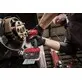 Pildil on mees, kes kasutab Milwaukee M18 B5-CR akutrelliga autol ratta kinnituspolte lahti keerates.