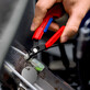 Pildil on näha Knipex külglõiketangid Slim 150 mm, mille punase käepideme küljes on sinine kinnitusnöör ja punane pael.