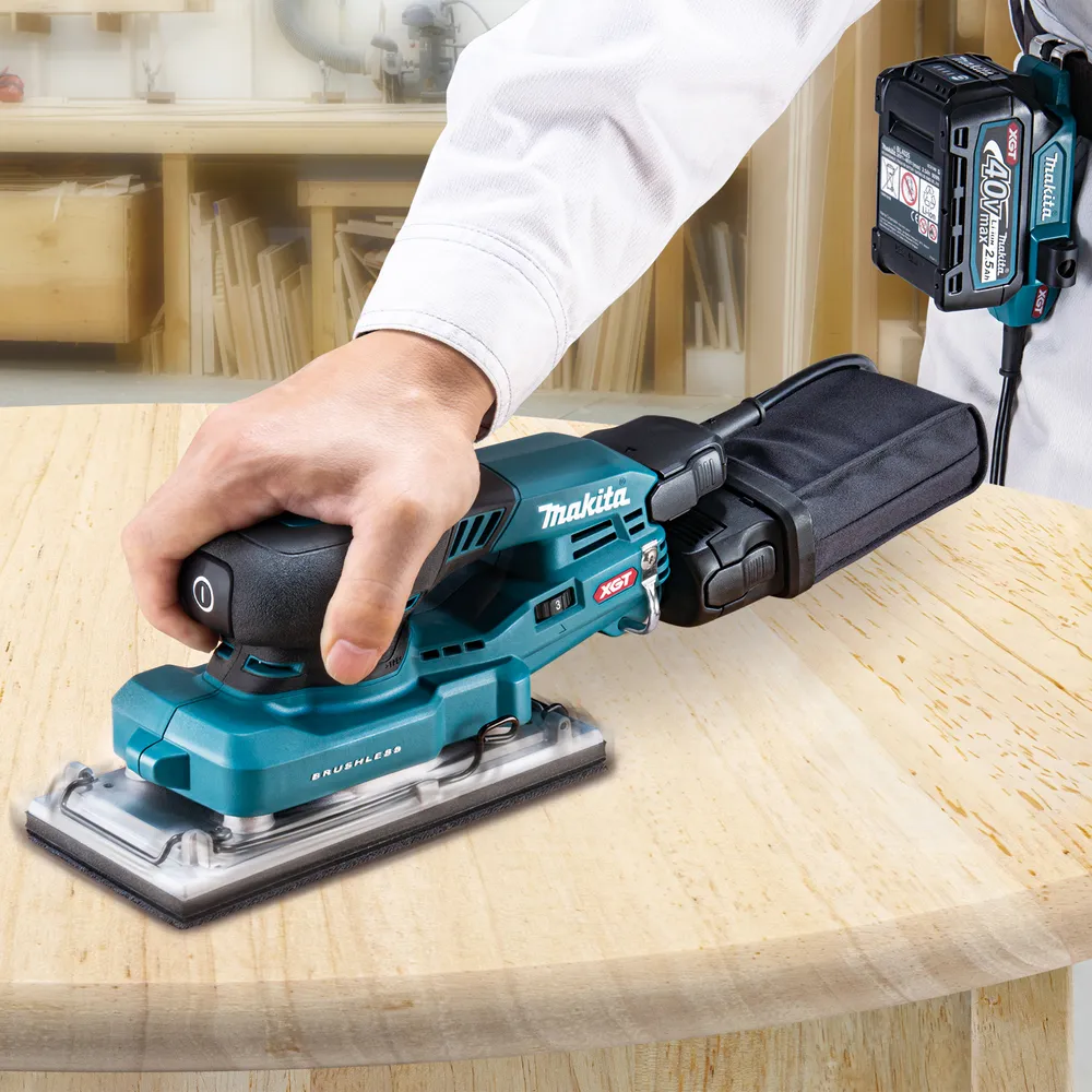 Pildil on näha Makita akutaldlihvija BO007CGZ koos tolmukotiga, mida kasutab töömees puidu lihvimiseks.