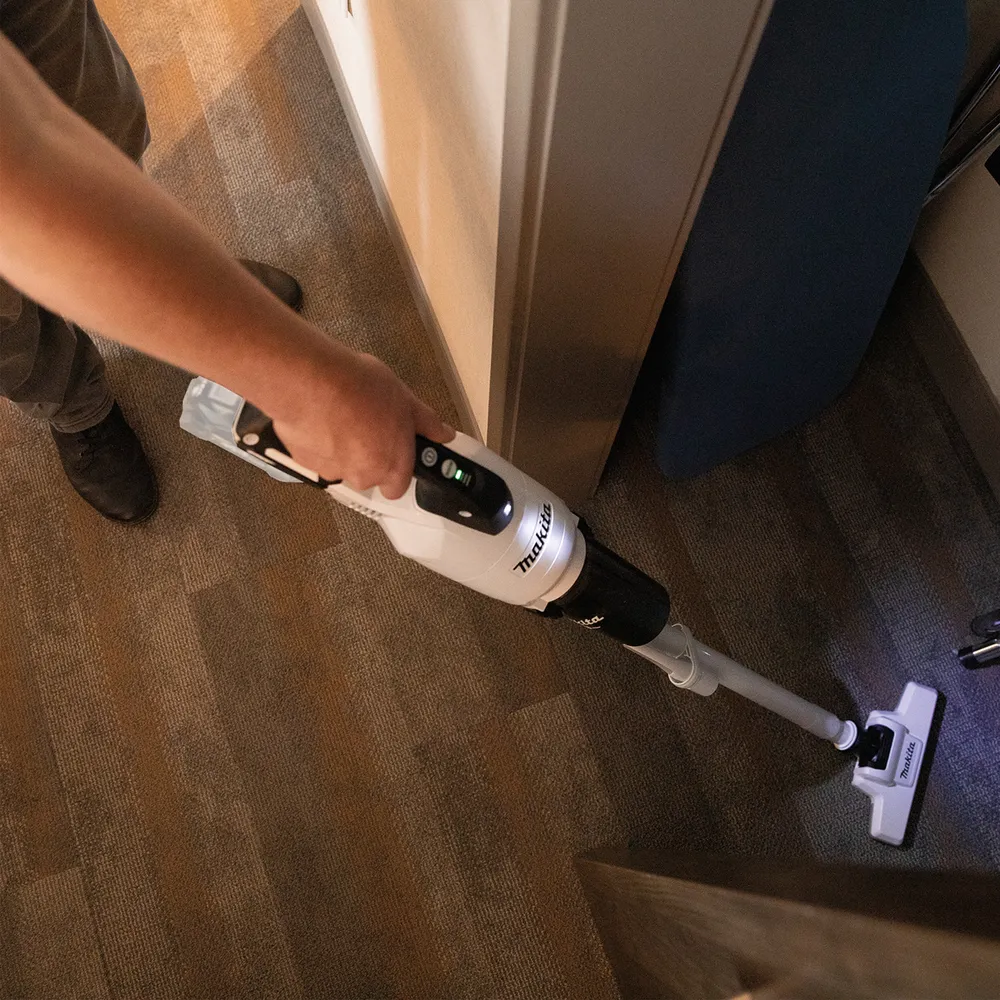 Pildil on näha Makita aku varstolmuimeja CL003GD203, mida hoitakse käes ja kasutatakse põrandal.