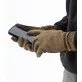 Pildil on inimene, kes kannab MECHANIX WEAR ColdWork FastFit Coyote talviseid kindaid ja kasutab nutitelefoni.