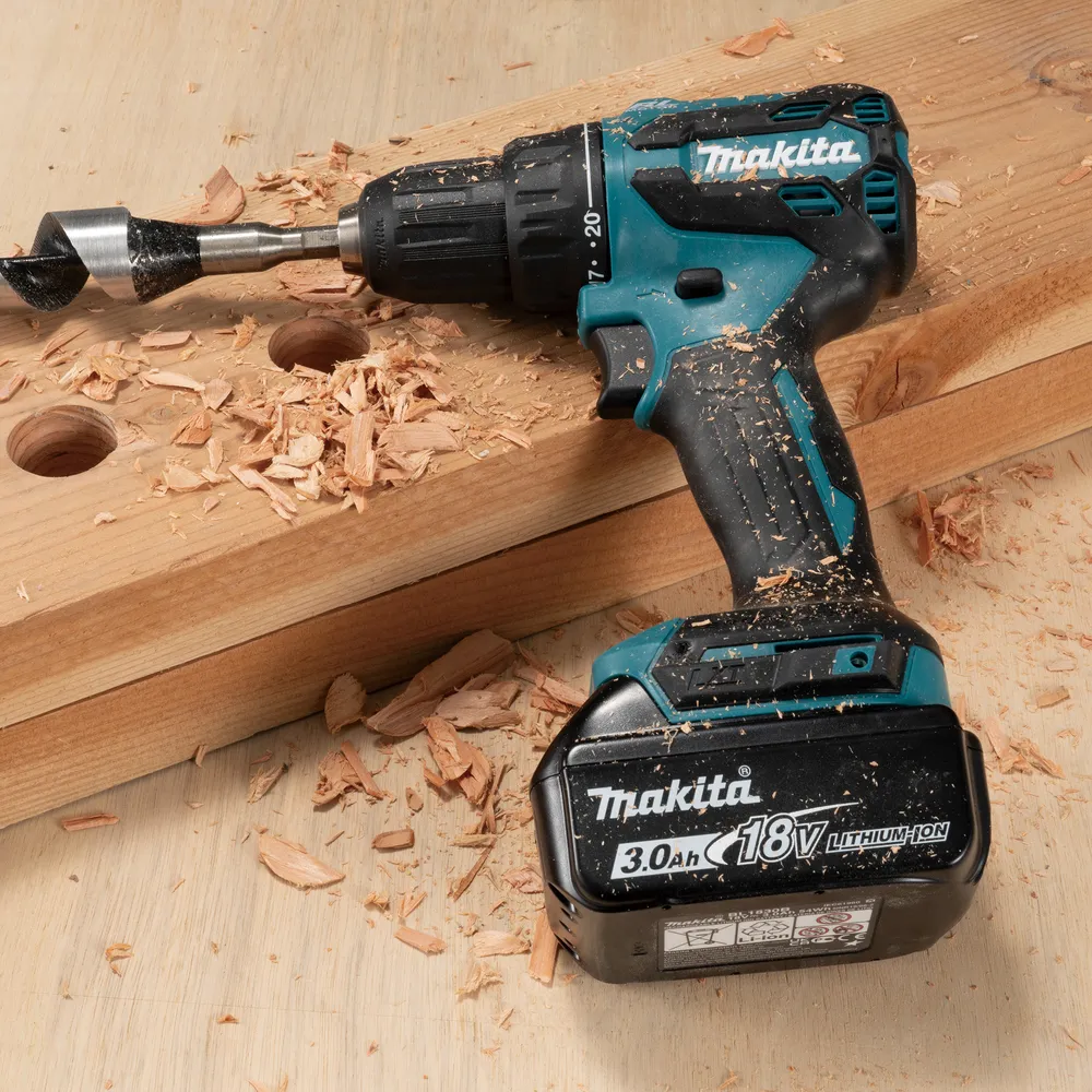 Pildil on Makita DDF490WF akutrell koos puuriga puidutükis, mille ümber on saepuru.