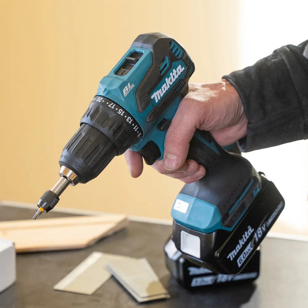 Pildil on käes Makita akutrell DDF490Z, ilma aku ja laadijata, valmis tööks, ning ümberringi on puidutööd.