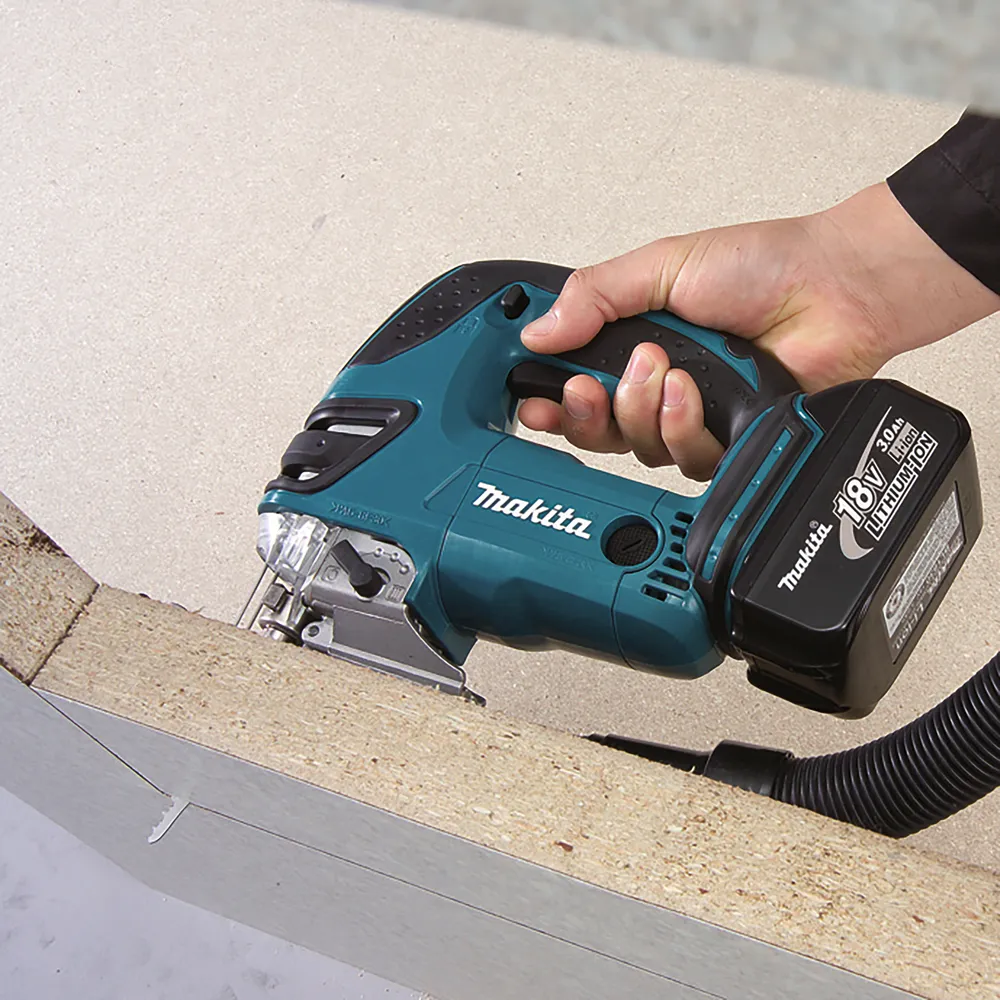 Pildil on Makita akutikksaag DJV180Z, mida hoitakse käes ja millega saetakse puidust plaati.