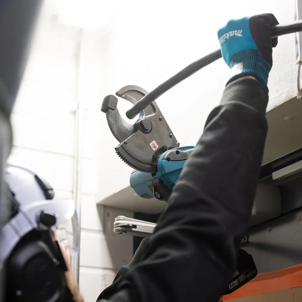 Pildil on Makita akukaablilõikur DTC101ZK, mida kasutab inimene koos kaitsevarustusega.