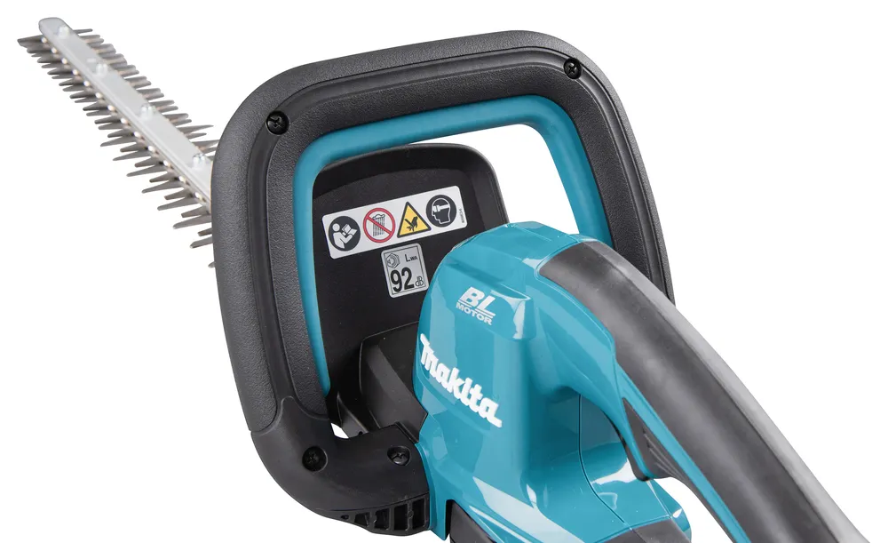 Pildil on detailne vaade Makita akuhekilõikurist DUH606RT, näidates selle käepidet, terasid ja ohutusmärgiseid.