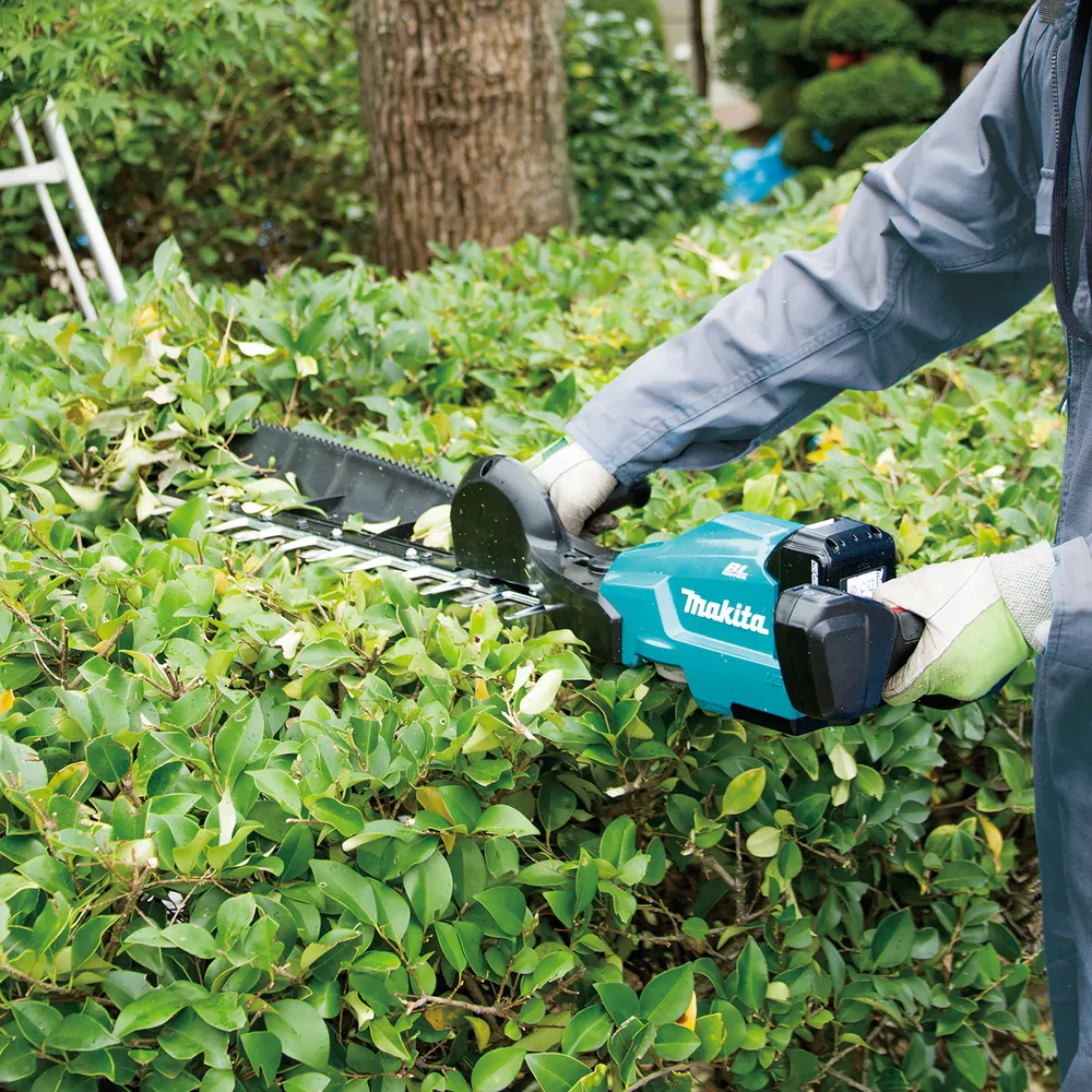 Pildil on näha Makita akuhekilõikurit DUH754SZ, millega inimene hekki lõikab.