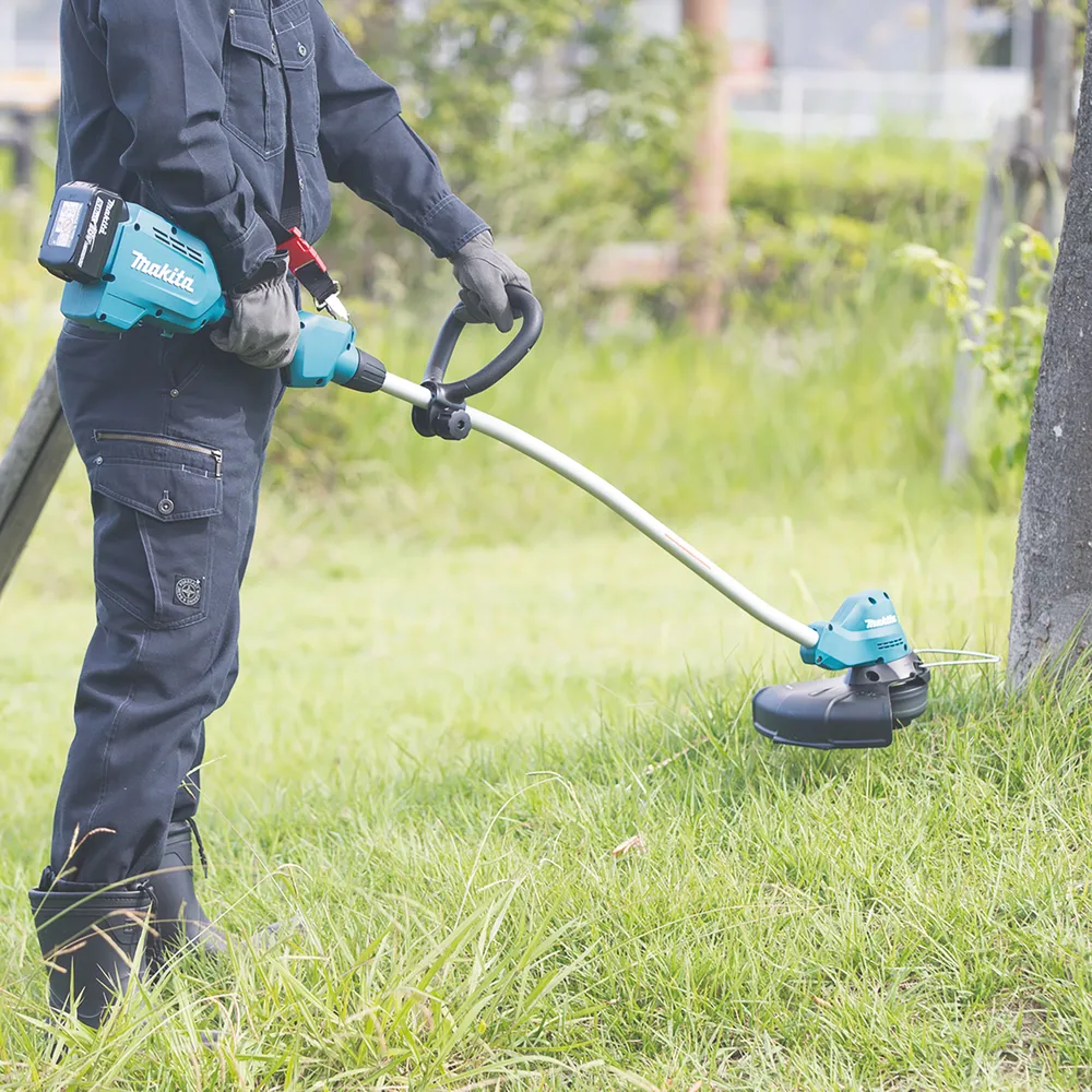 Pildil on Makita akutrimmer DUR189Z, mida inimene kasutab niitmiseks.