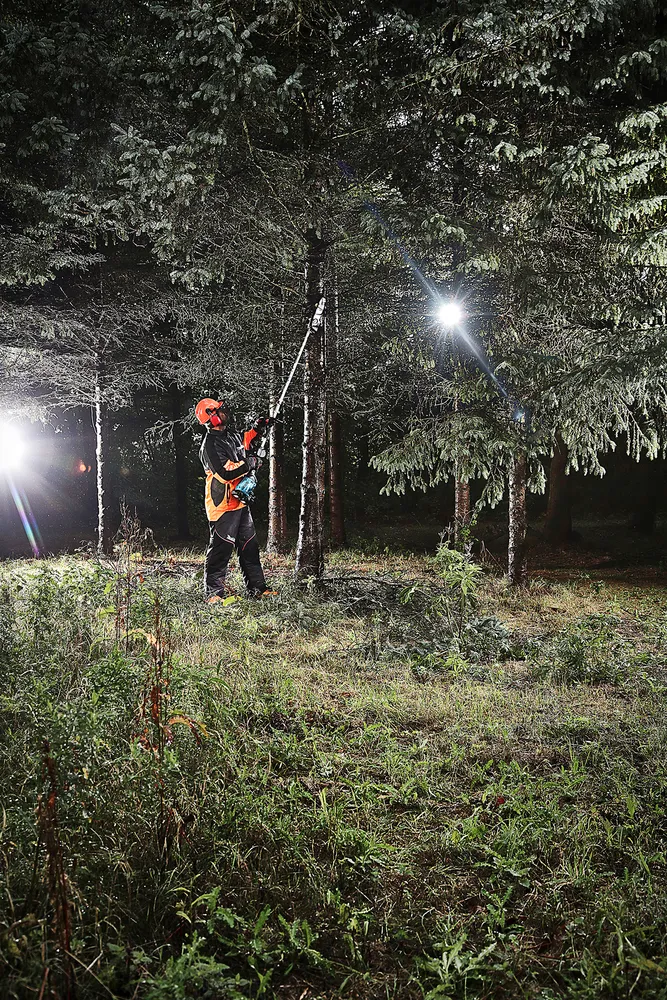 Pildil on näha Makita vahetatavate tarvikutega akutrimmer DUX60ZM4, mida kasutatakse puidu lõikamiseks pimedas metsas.