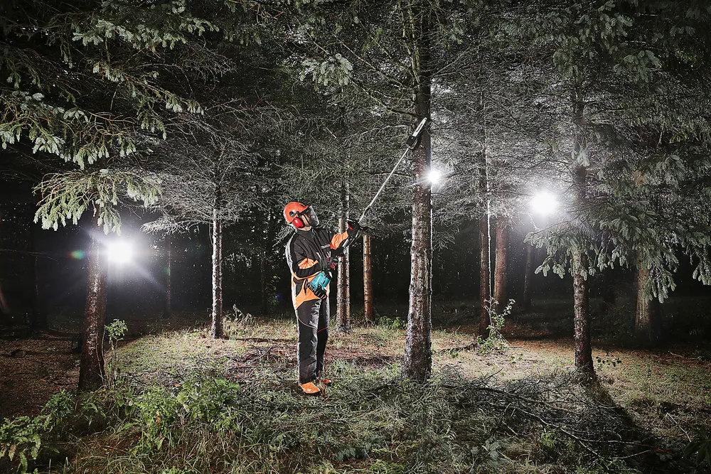 Pildil on Makita vahetatavate tarvikutega akutrimmer DUX60ZM4, mida kasutatakse metsatehnika töös, kus inimene töötab...